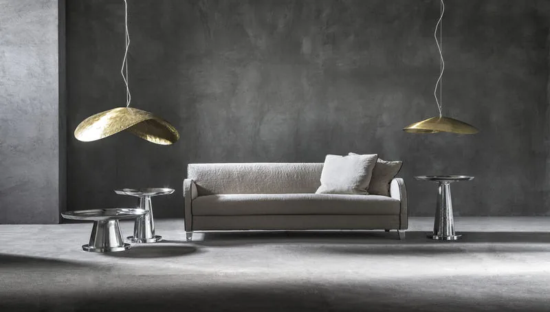 Living room with brass pendant lamps, sofa and polished metal accent tables by The Paradise